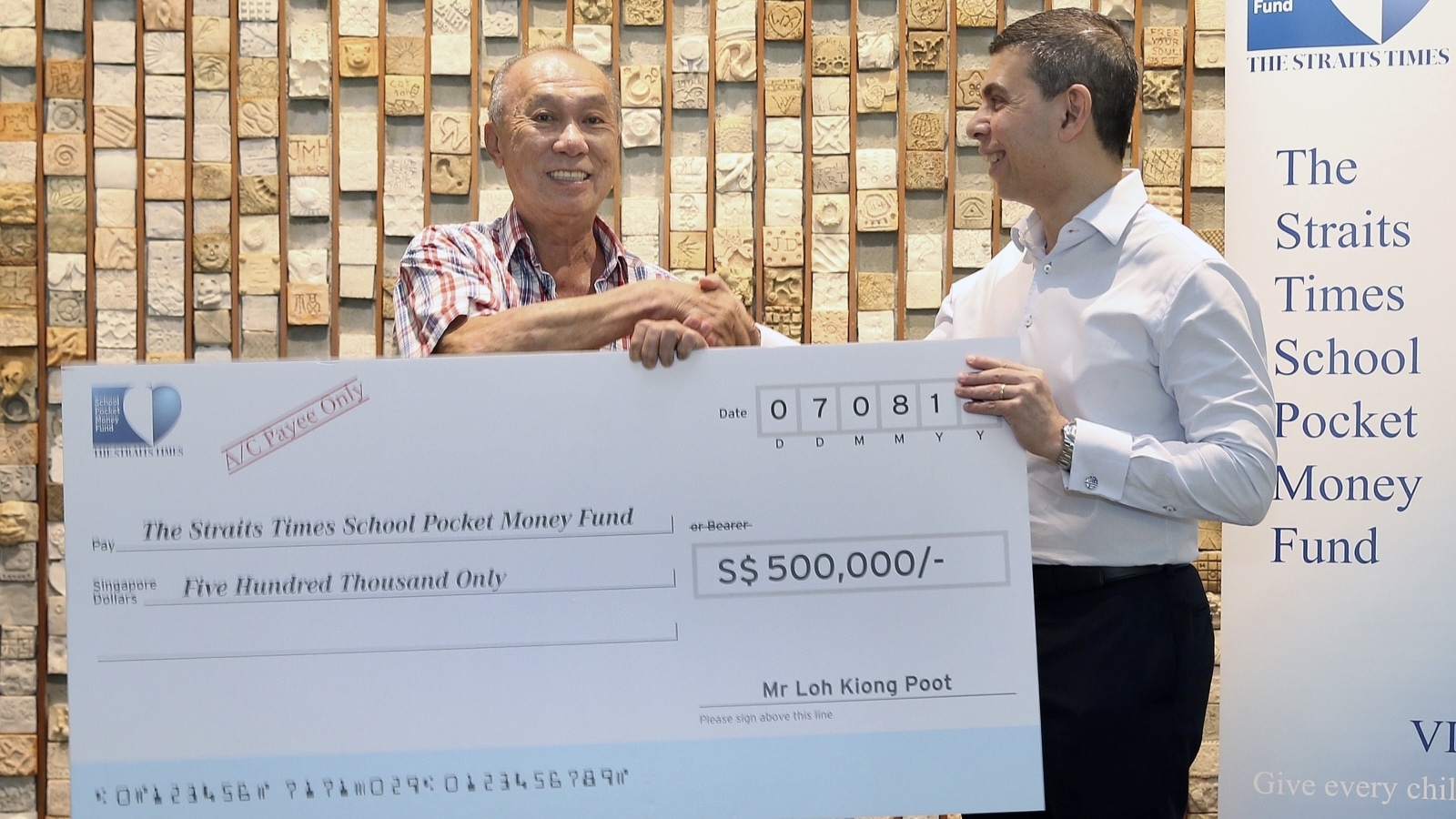 Mr. Loh presenting a mock cheque to Straits Time School Pocket Money Fund Chairman, Warren Fernandez, in 2018 (Photo: The Straits Time School Pocket Money Fund)